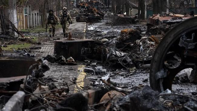 soldiers walk amid destroyed russian tanks in bucha