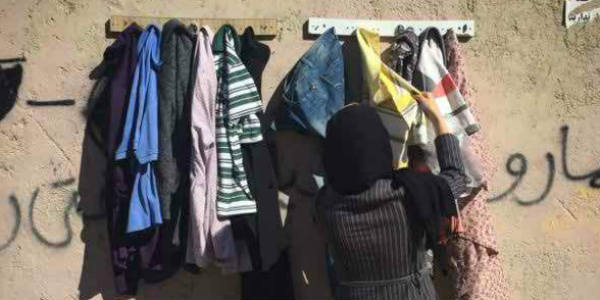 helping poor people by giving warm cloth at a wall in iran