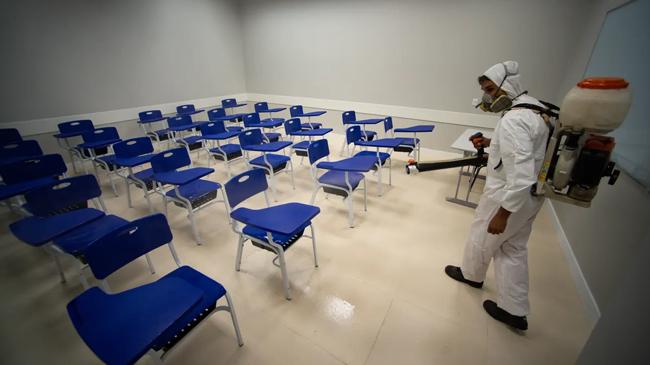 a man sanitizing a classroom