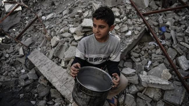 a palestinian child holding empty pot