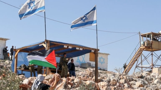 a palestinian flag next to the israeli outpost of evitar
