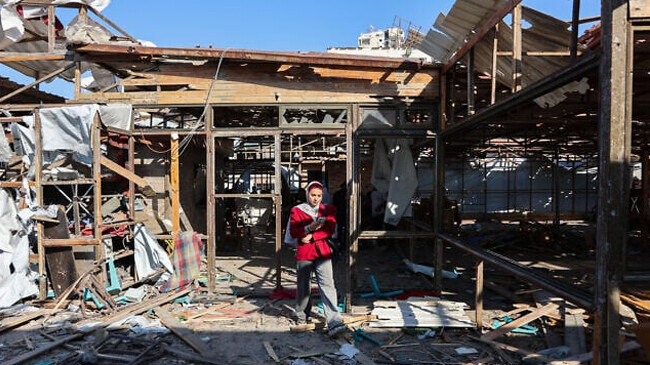 a palestinian woman walks on debris at al baqa cafeteria