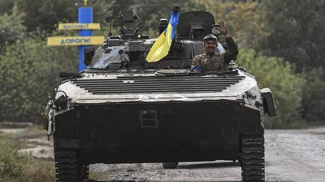 a soldier waves from a ukrainian tank