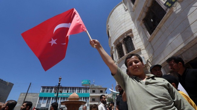 a young syrian raises a turkish flag