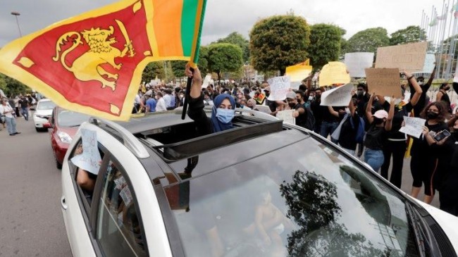a woman waves a sri lankan flag from inside a car