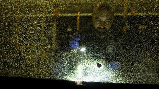 an israeli security officer stands behind a shattered window of a bus