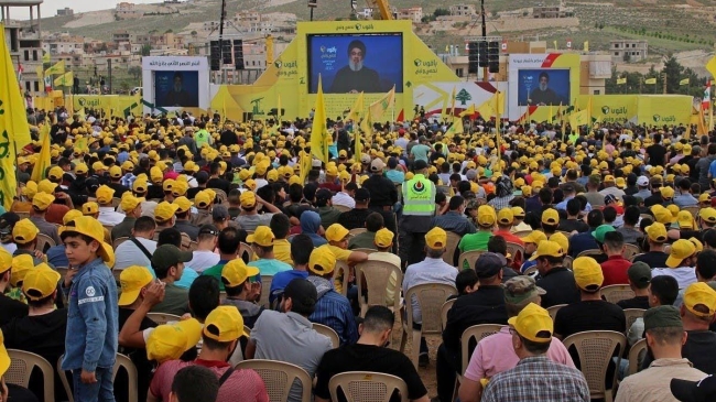hezbollah leader hassan nasrallah on a screen during a campaign