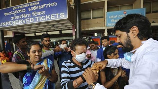 india railstation people rubbing hand with sanitizer