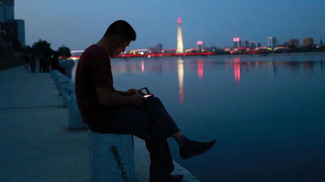 man uses phone sitting taedong river pyongyang