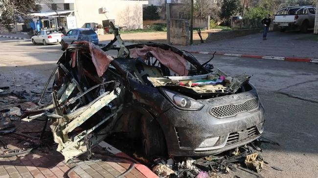 palestinians inspect a destroyed vehicle