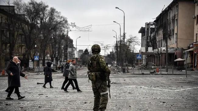 people pass by a russian soldier in central mariupol