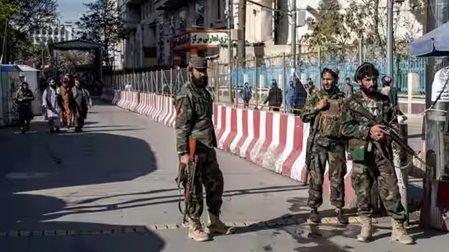 taliban fighters stand guard at the explosion site