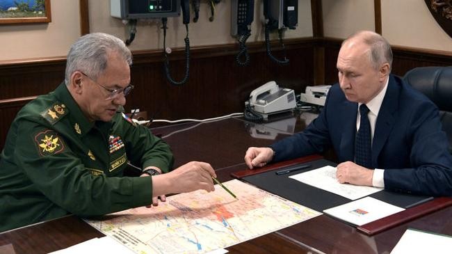 vladimir putin listens to defense minister sergei shoigu